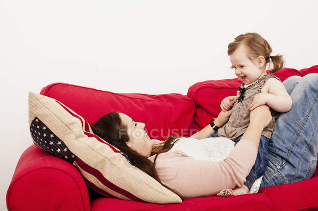 Girl sitting on mothers stomach — Stock Photo