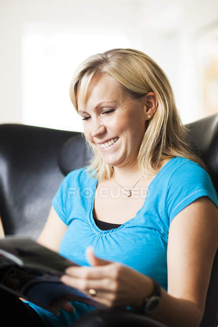 Femme souriante lecture magazine — Photo de stock