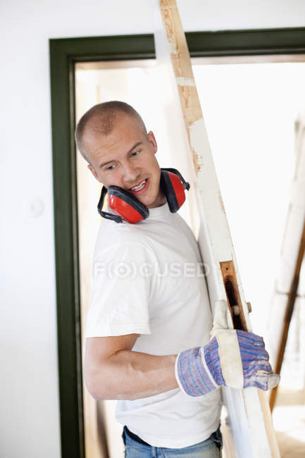 Young man carrying wooden doo — Stock Photo