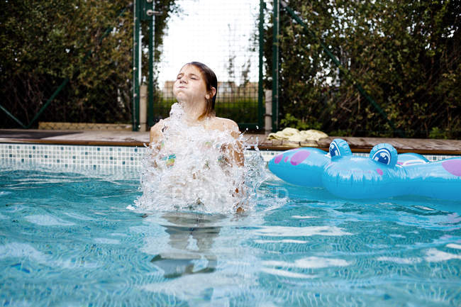 Menina nadando com jangada na piscina — Fotografia de Stock