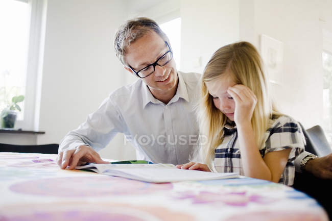 Mature father assisting daughter in homework at home — Stock Photo