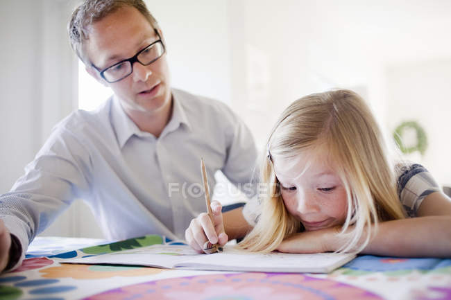 Father assisting daughter in homework at home — Stock Photo