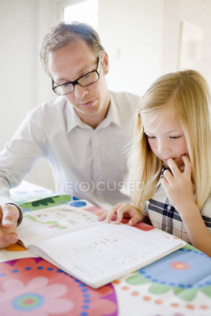 Père aidant fille dans les devoirs à la maison — Photo de stock