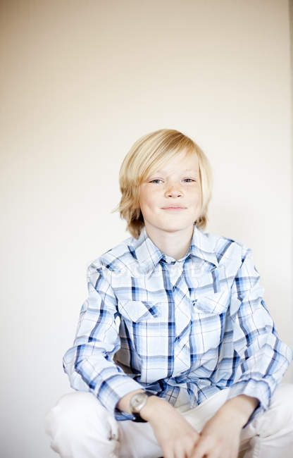 Blonde préadolescent garçon assis contre le mur à la maison — Photo de stock