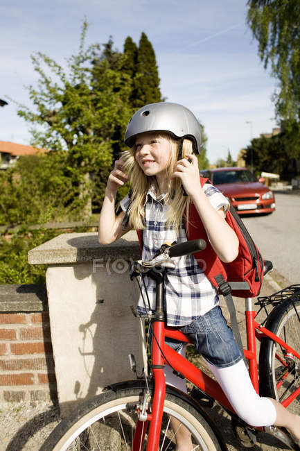 Дівчина тримає шолом, стоячи з велосипедом в сонячний день — стокове фото