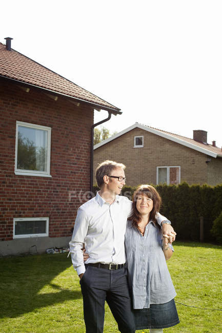 Couple adulte moyen debout dans la cour arrière en face de la maison — Photo de stock