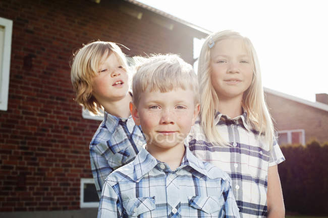 Ritratto ad angolo basso di tre fratelli nel cortile sul retro — Foto stock