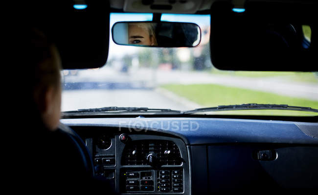 Partial reflection of person in rear-view mirror in car — Stock Photo