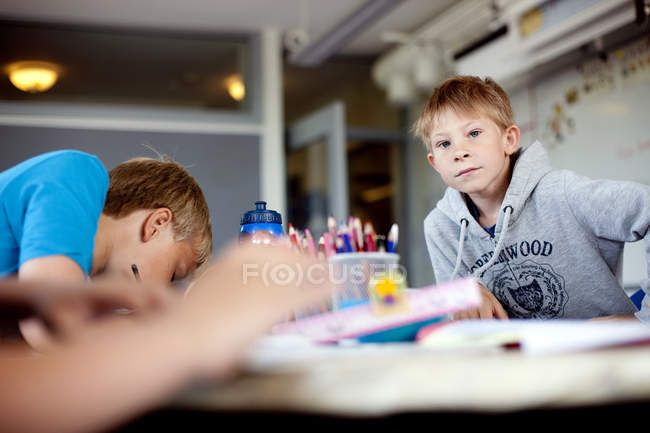 Хлопці сидять за столом у класі — стокове фото