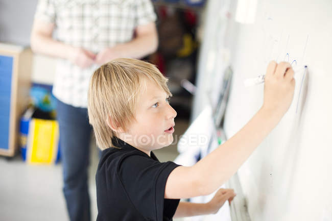 Junge schreibt auf Whiteboard — Stockfoto