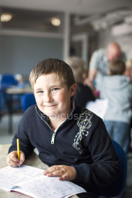 Усміхнений школяр сидить за столом — стокове фото