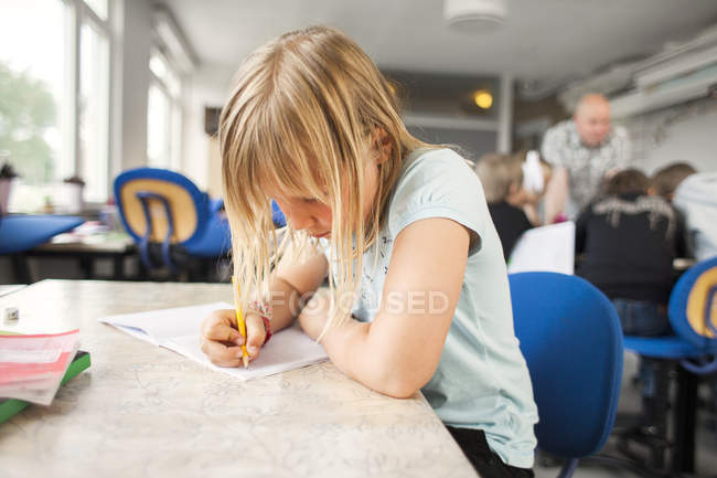 Schoolgirl writing in book — Stock Photo
