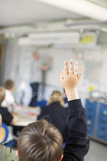 Vista trasera del niño levantando la mano - foto de stock