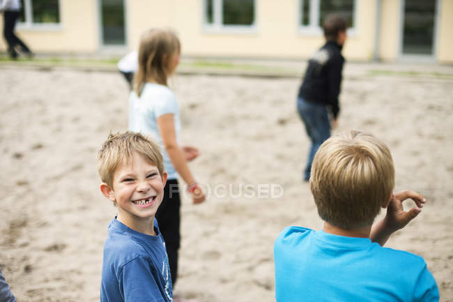 Colegial jugando con amigos en el patio - foto de stock