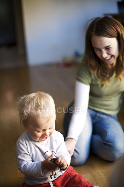 Высокоугольный вид улыбающейся матери, играющей с сыном дома — стоковое фото