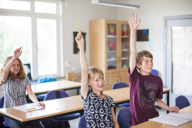 Junior high students raising hands — Stock Photo