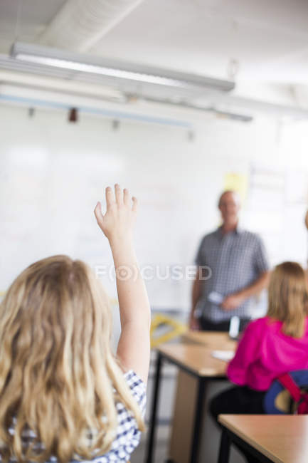 Schoolgirl raising hand — Stock Photo