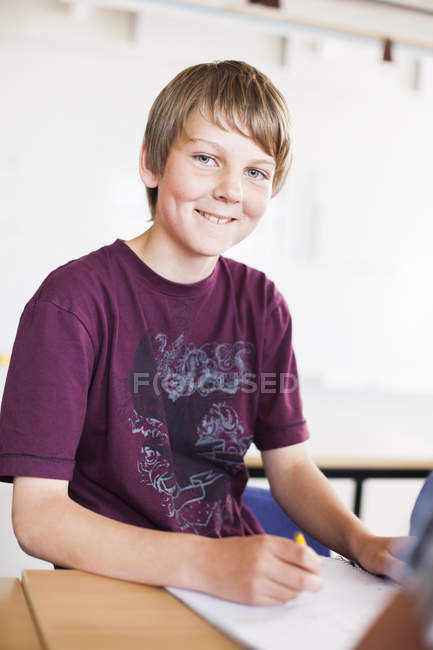 Feliz estudiante sentado en el escritorio - foto de stock