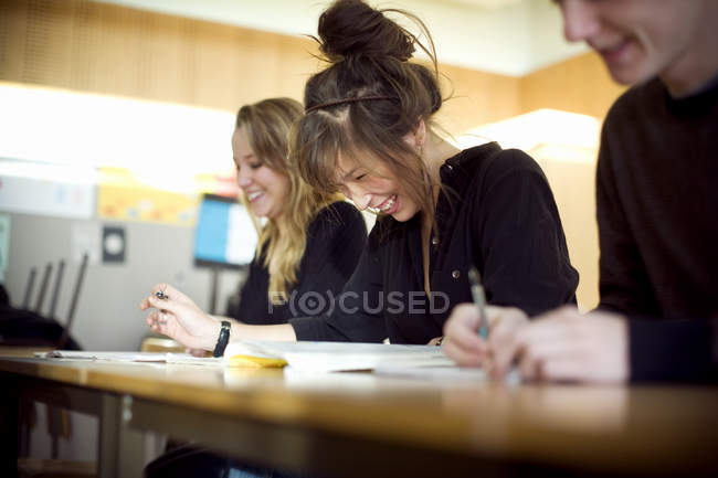 Lächelnde Schüler, die am Schreibtisch im Klassenzimmer lernen — Stockfoto
