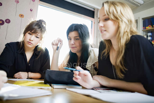 Estudantes do sexo feminino estudando na mesa em sala de aula — Fotografia de Stock