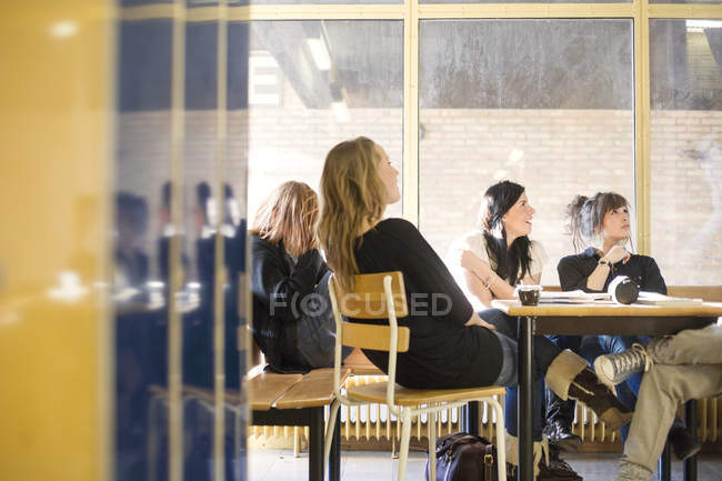 Étudiants du secondaire assis à table dans la salle commune — Photo de stock
