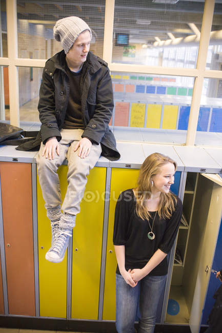 Homem sentado em armários com amigo feminino na universidade — Fotografia de Stock