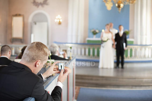 Hombre fotografiando novia y novio - foto de stock