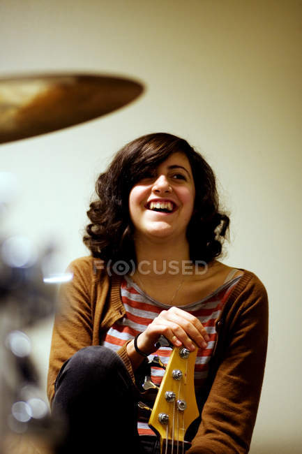 Cropped view of smiling woman sitting and holding bass guitar — Stock Photo