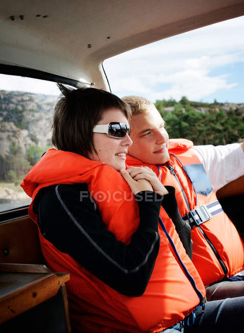 Casal sorridente vestindo coletes salva-vidas enquanto viaja em barco — Fotografia de Stock