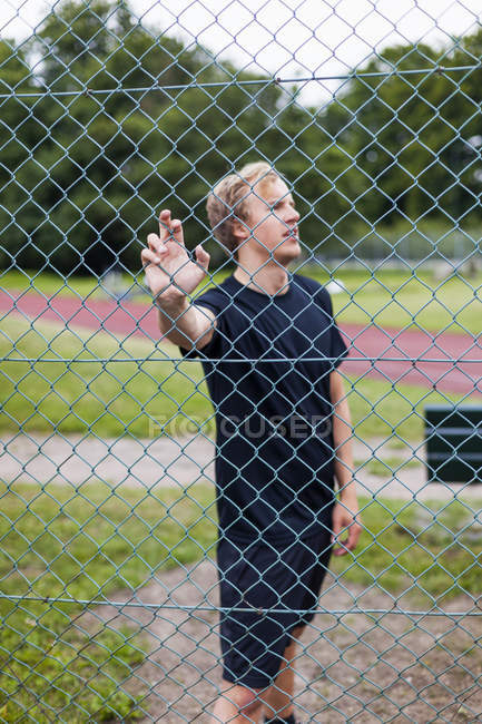 Athlete standing by chainlink fence — Stock Photo