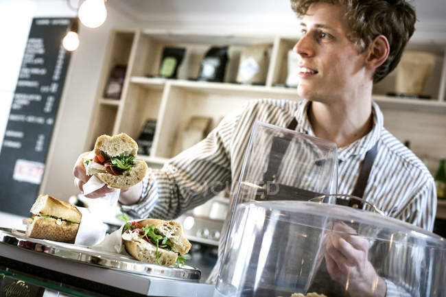 Jovem garçom servindo sanduíche — Fotografia de Stock