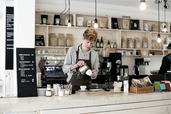 Junger Barista bereitet Cappuccino zu — Stockfoto