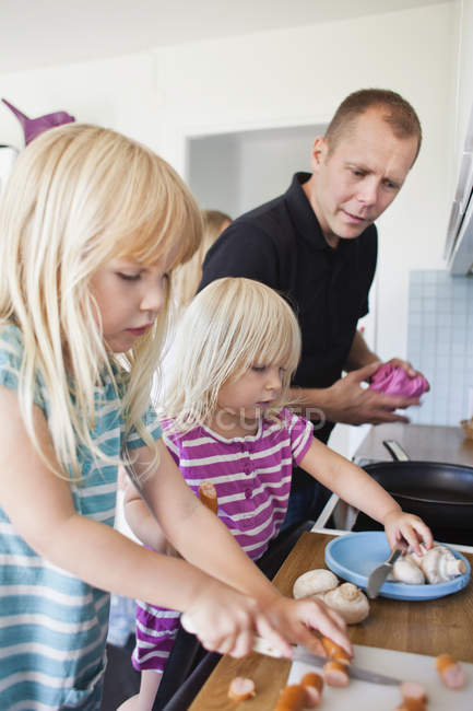 Дочь режет сосиски на кухне — стоковое фото