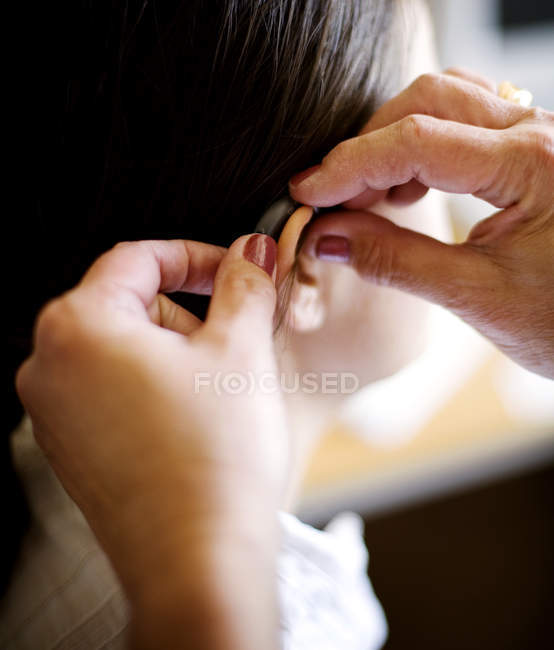 Mains mettant aide auditive à la femme — Photo de stock