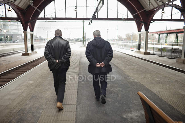 Мужчины, идущие по железнодорожной станции — стоковое фото