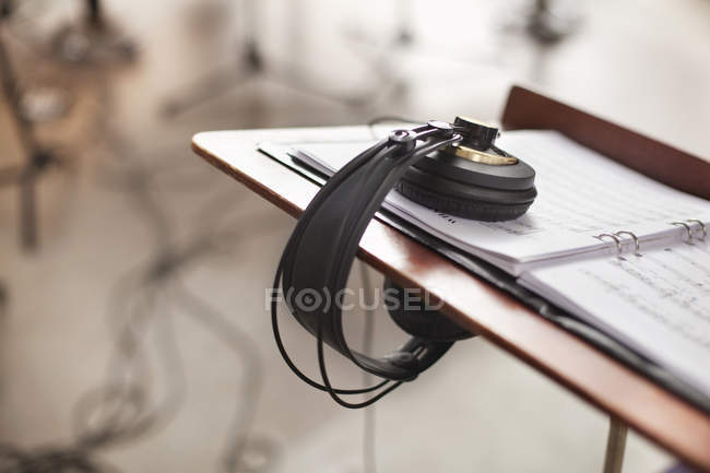 Headphones on music sheet at desk — Stock Photo