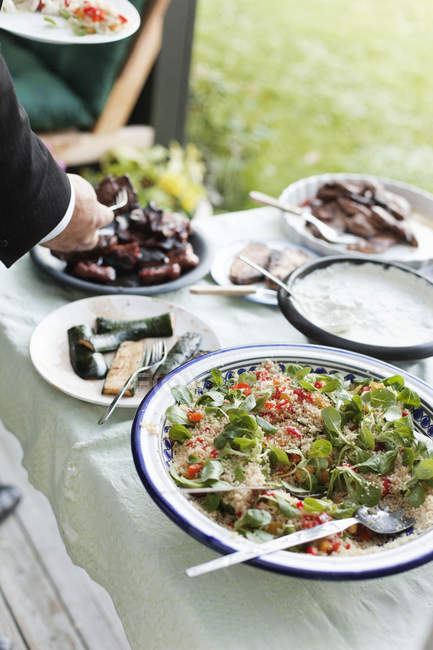 Homem servindo comida na mesa de jantar ao ar livre — Fotografia de Stock