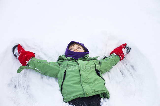Мальчик делает снежного ангела — стоковое фото