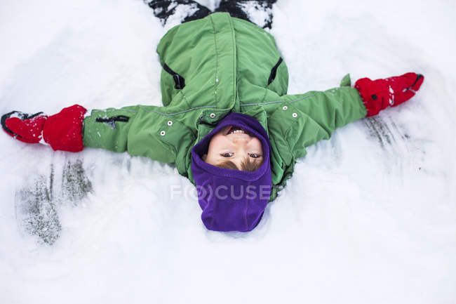 Счастливый мальчик делает снежного ангела — стоковое фото