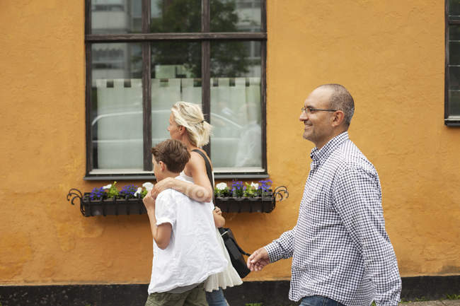 Famiglia che cammina contro edificio arancione — Foto stock