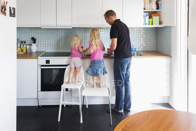Padre e hijas que trabajan en la cocina - foto de stock