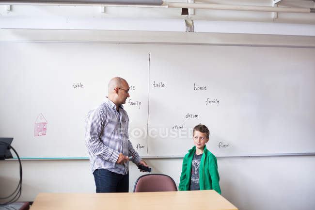 Teacher talking to schoolboy in classroom — Stock Photo