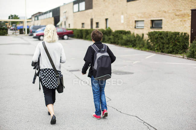 Enseignant et écolier marchant dans la rue — Photo de stock