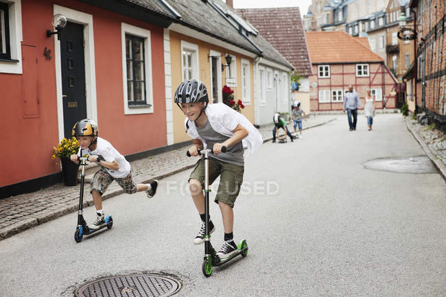Boys riding push scooters — Stock Photo