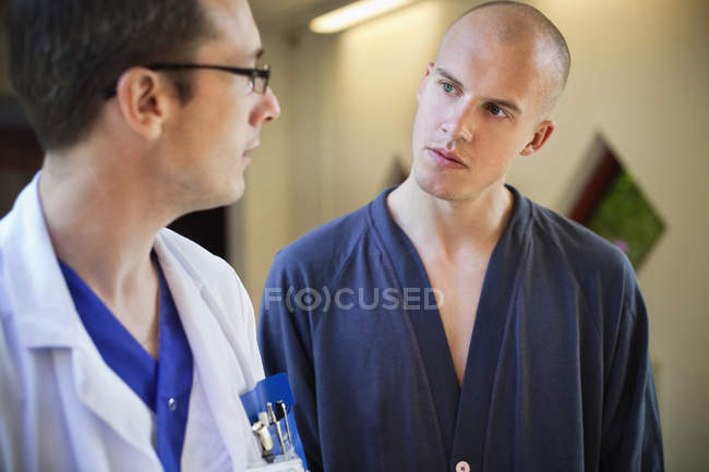 Docteur discutant des dossiers avec le patient masculin — Photo de stock