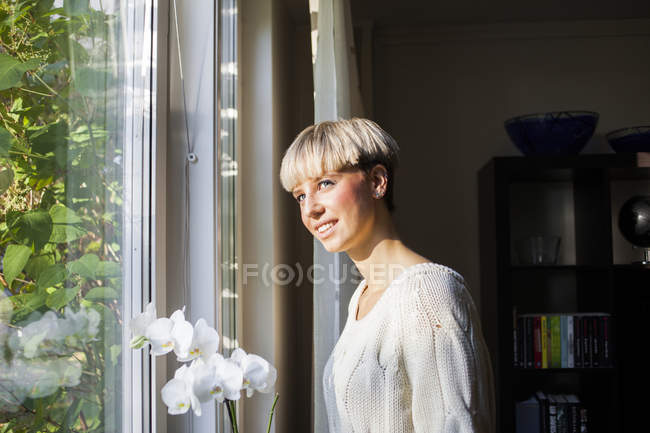 Mulher por flores brancas das orquídeas — Fotografia de Stock