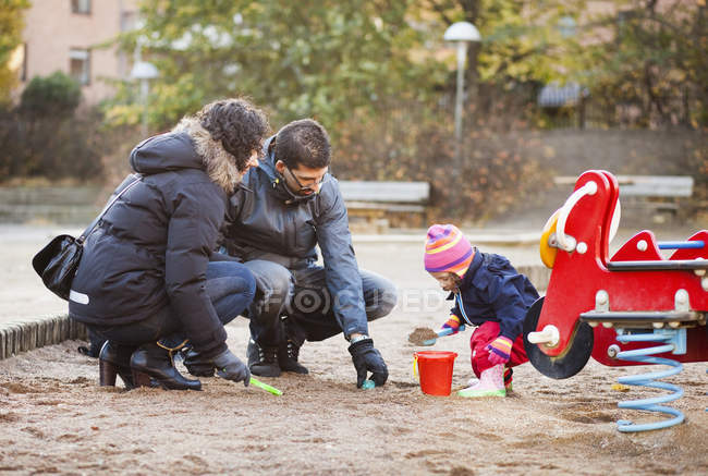 Familia jugando en la arena - foto de stock