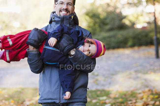 Padre juguetón llevando hija - foto de stock