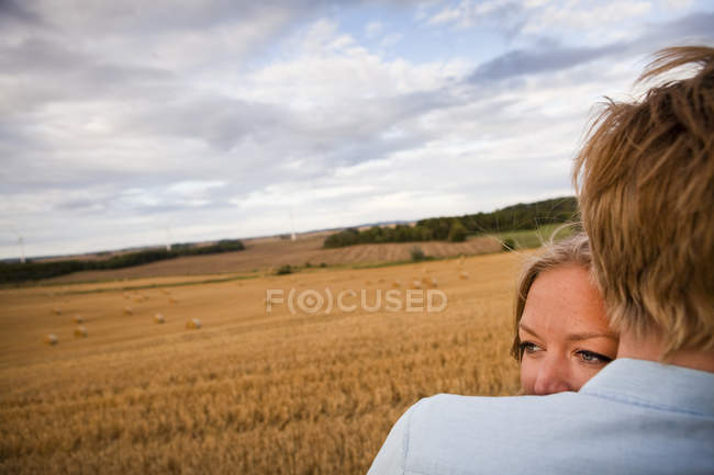 Couple embracing on field — Stock Photo