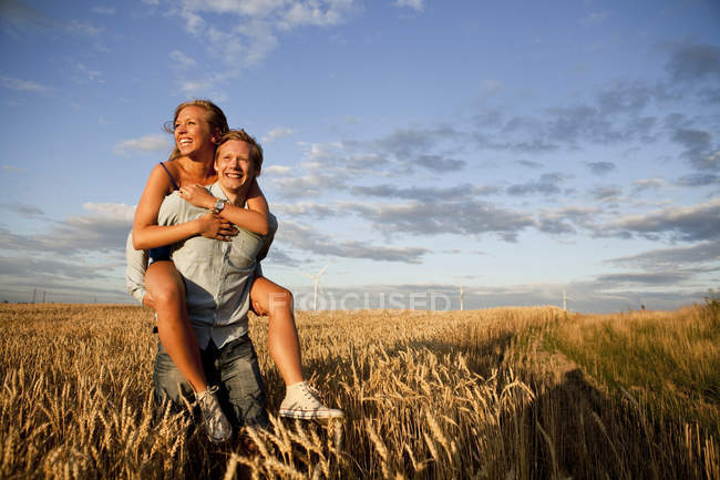 Homme donnant piggyback à la femme — Photo de stock